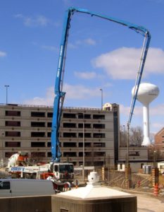 Concrete pumping truck providing concrete to job site 